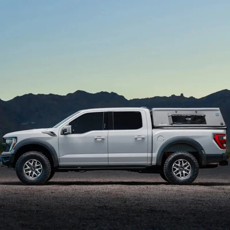 Side view of a white truck with the 5.5' Bed Air-Topper CAP installed, set against a mountain backdrop at dusk.