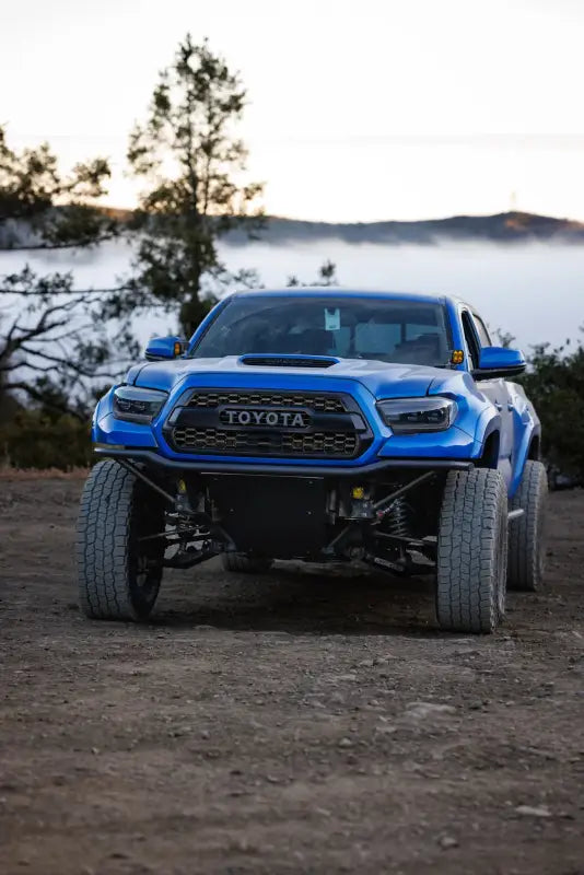 Blue Toyota Tacoma off-road truck with custom Pre Runner Bumper, showcasing lower radiator support and relocating power steering brackets