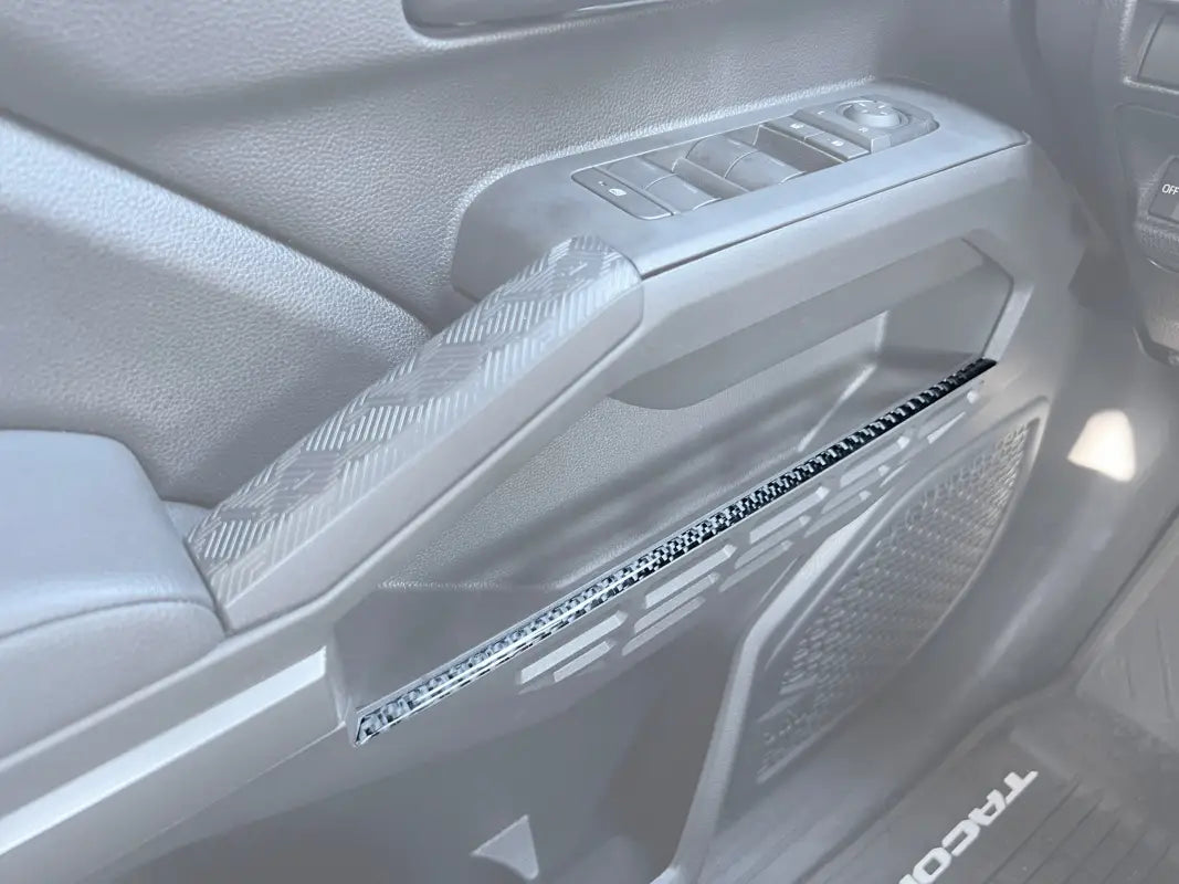 Carbon fiber door storage line accent trim installed on the interior of a 2024-2025 Toyota Tacoma, enhancing the vehicle's aesthetic.