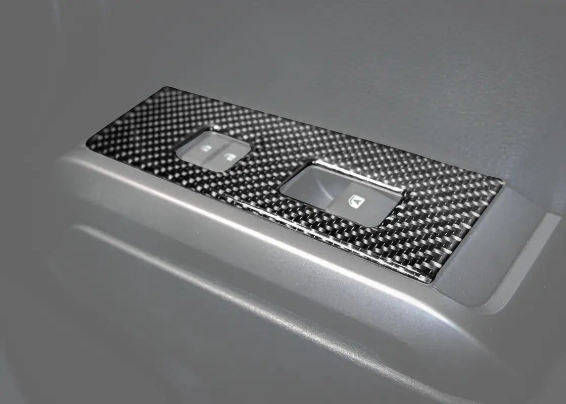 Carbon fiber door switch panel accent overlay installed on a 2016-2023 Toyota Tacoma interior door, enhancing style and protection.
