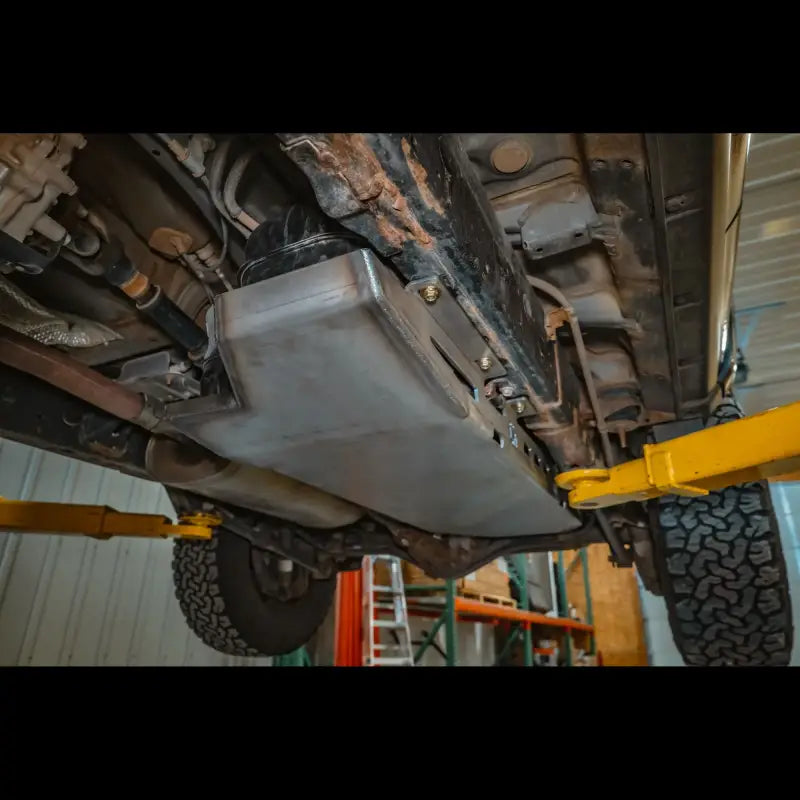 Undercarriage view of a 5th Gen 4Runner with a steel skid plate installed, highlighting bolt-on design and rugged fuel tank protection.