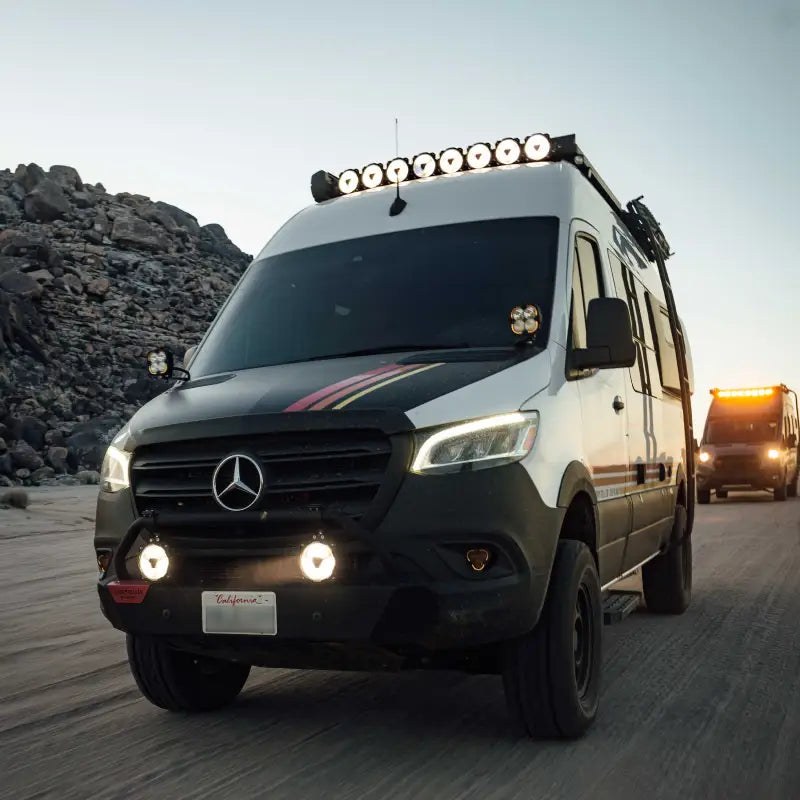Mercedes Sprinter van equipped with Gravity® Titan™ 6" LED lights and roof-mounted light bar, driving on rugged terrain.