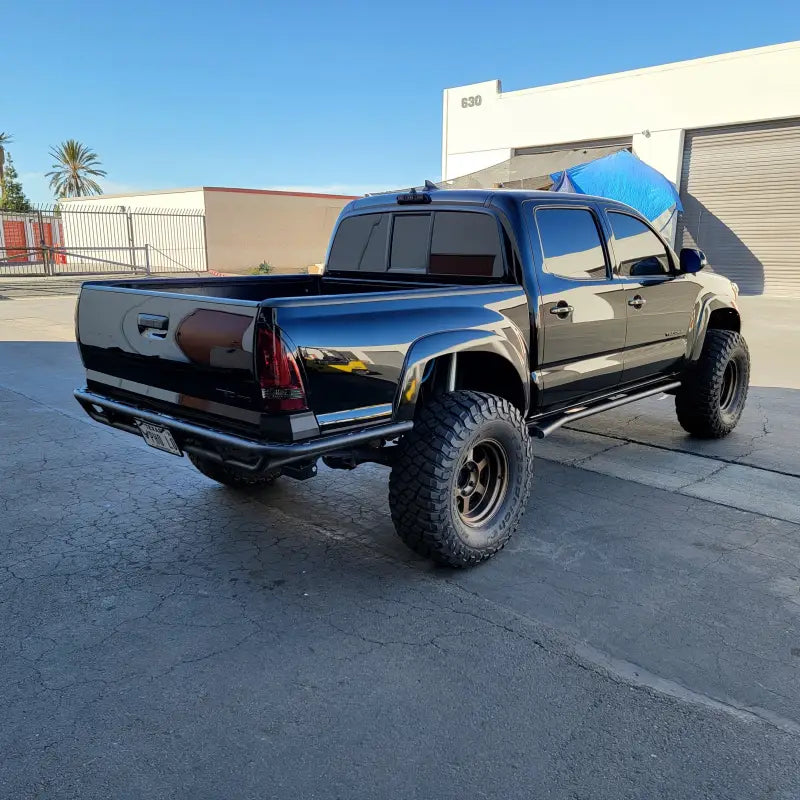 2005-2015 HC Rear Tube Bumper on a black 3rd Gen Toyota Tacoma with high clearance design, 2-inch hitch receiver, and rugged off-road tires.