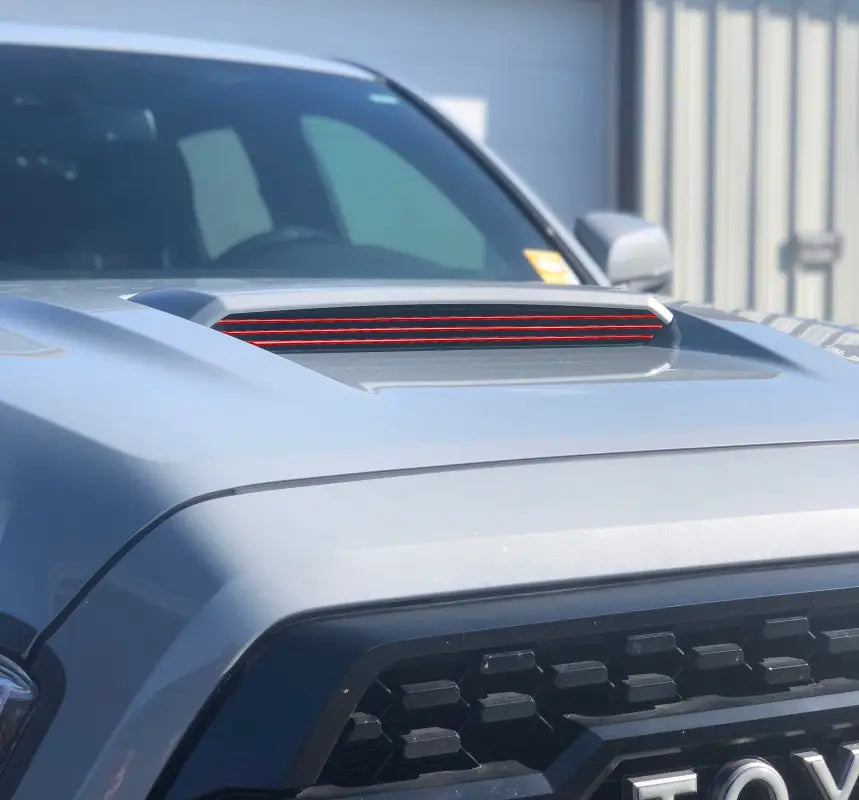 Close-up of red inner hood scoop line accents on a Toyota Tacoma, showcasing precise fitment and bold styling.