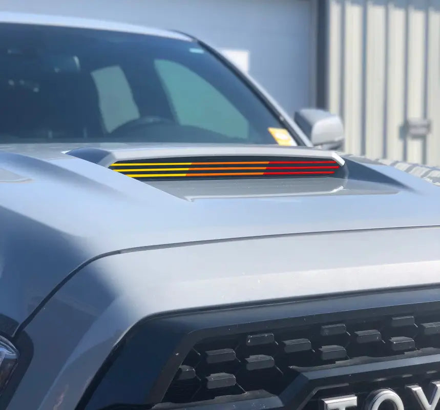 Tri-color inner hood scoop line accents in yellow, orange, and red installed on a Toyota Tacoma, adding a vibrant touch.