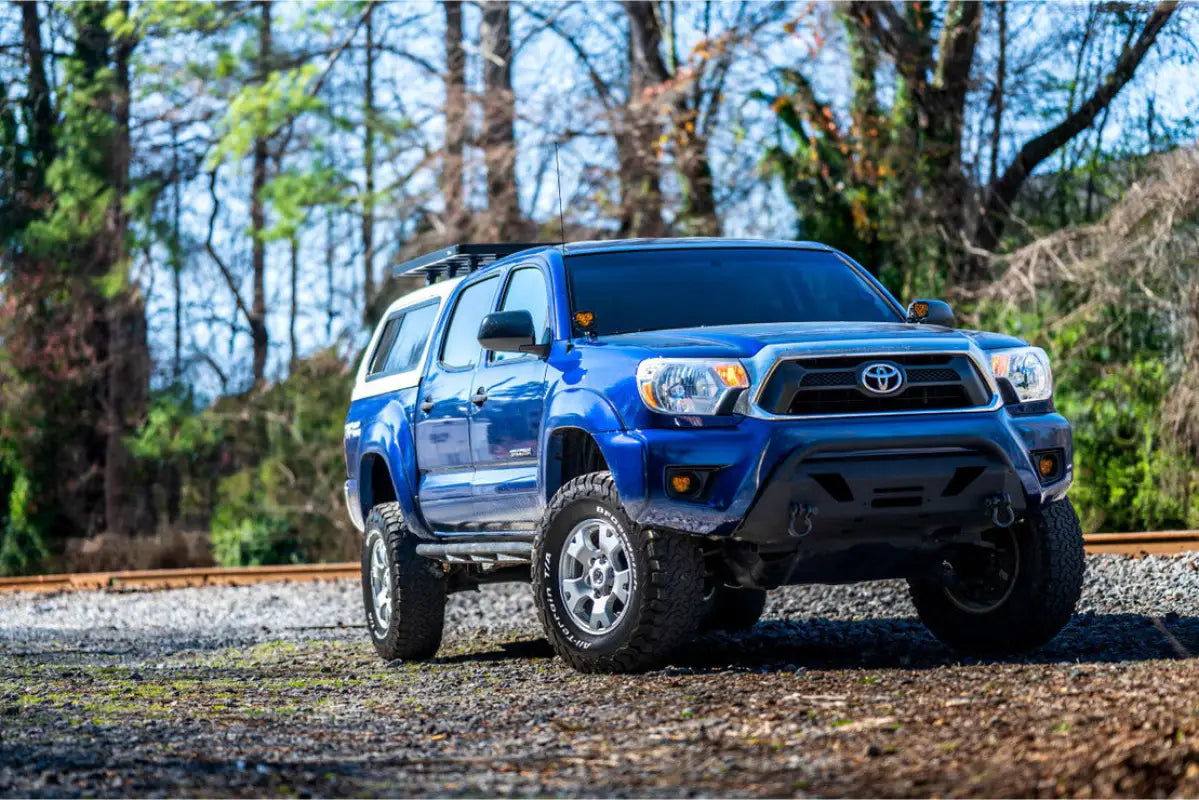 Blue 2012-2015 Toyota Tacoma equipped with Morimoto 4Banger LED Fog Lights, parked outdoors with a rugged setup.