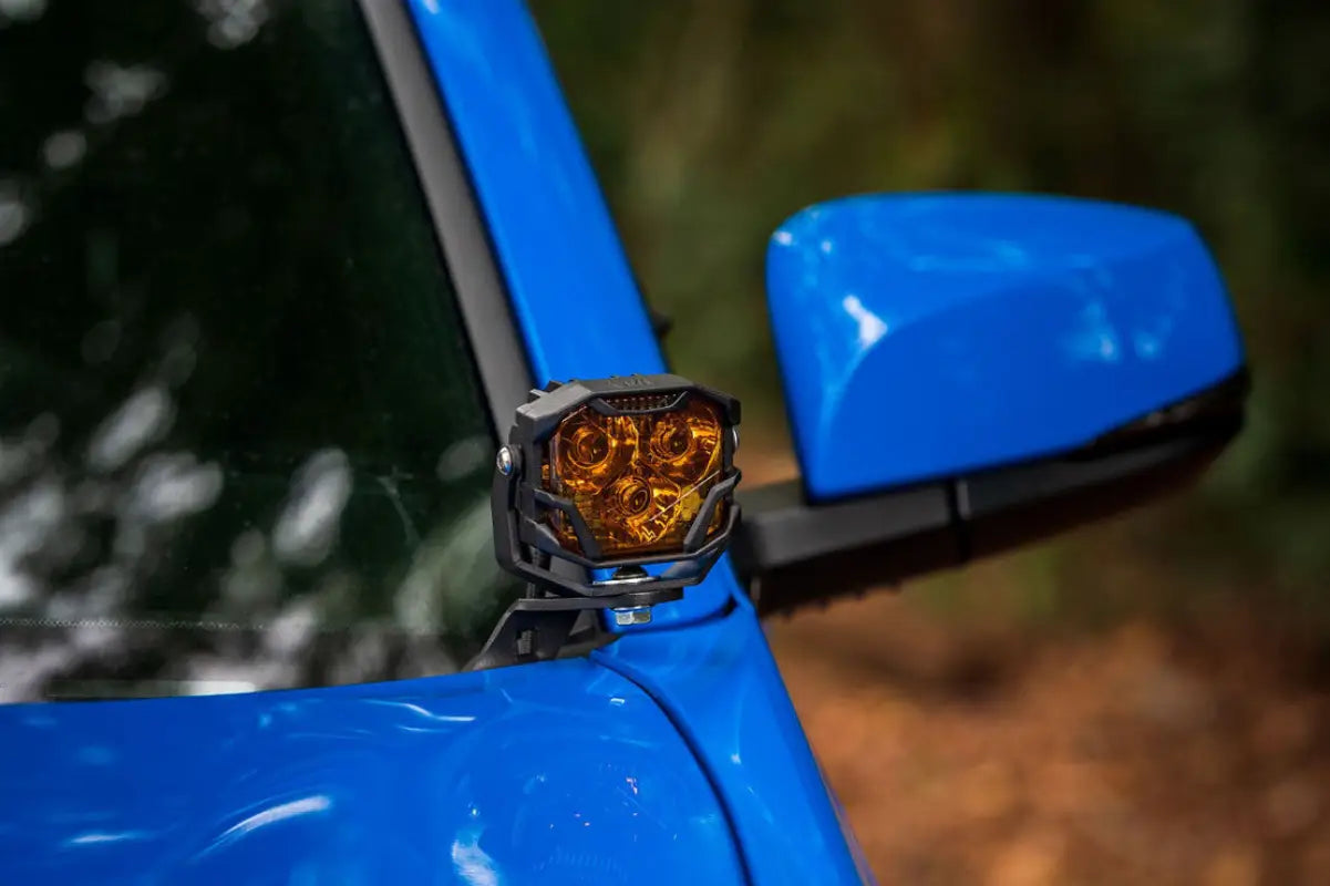 Close-up of Morimoto HXB 4Banger Ditch Light with amber lens mounted on a blue Tacoma 2016-2023, designed for off-road use.