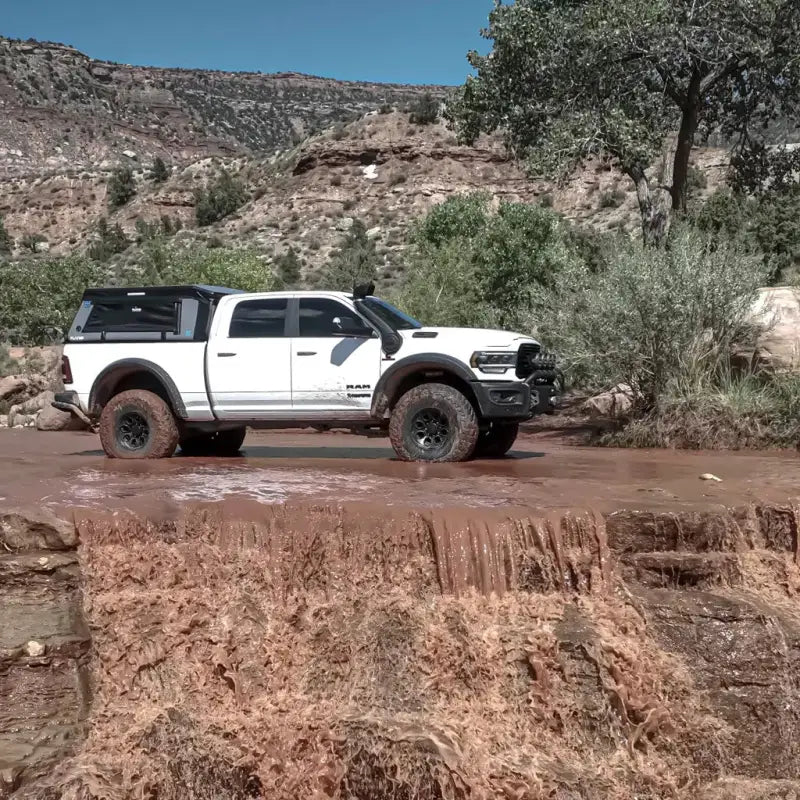 MR - Full-Size 6.4' Bed air-topper shell on a white truck navigating a muddy terrain, showcasing its rugged performance.