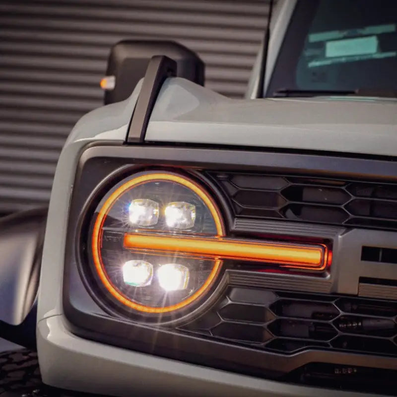 Close-up of NOVA-Series LED projector headlights installed on a Ford Bronco, showcasing amber DRL and turn signal functionality.