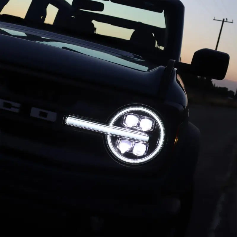 Ford Bronco with NOVA-Series LED projector headlights at dusk, featuring bright white DRL and modern lighting design.