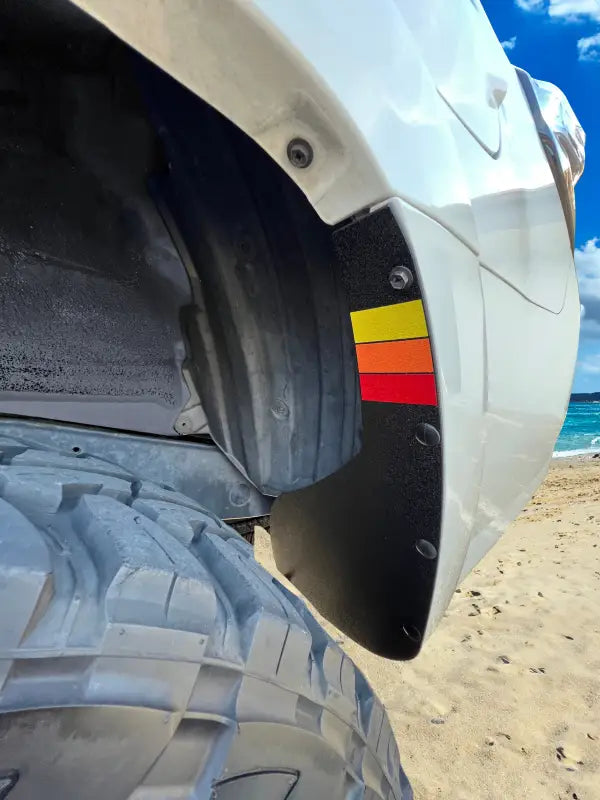 Close-up view of a rear mud flap delete kit on a Toyota 4Runner, showcasing a black design with vibrant red, yellow, and orange accents.