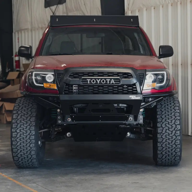 Straight-on view of a red Toyota Tacoma fitted with the Rock Runner front bumper, designed for off-road durability.
