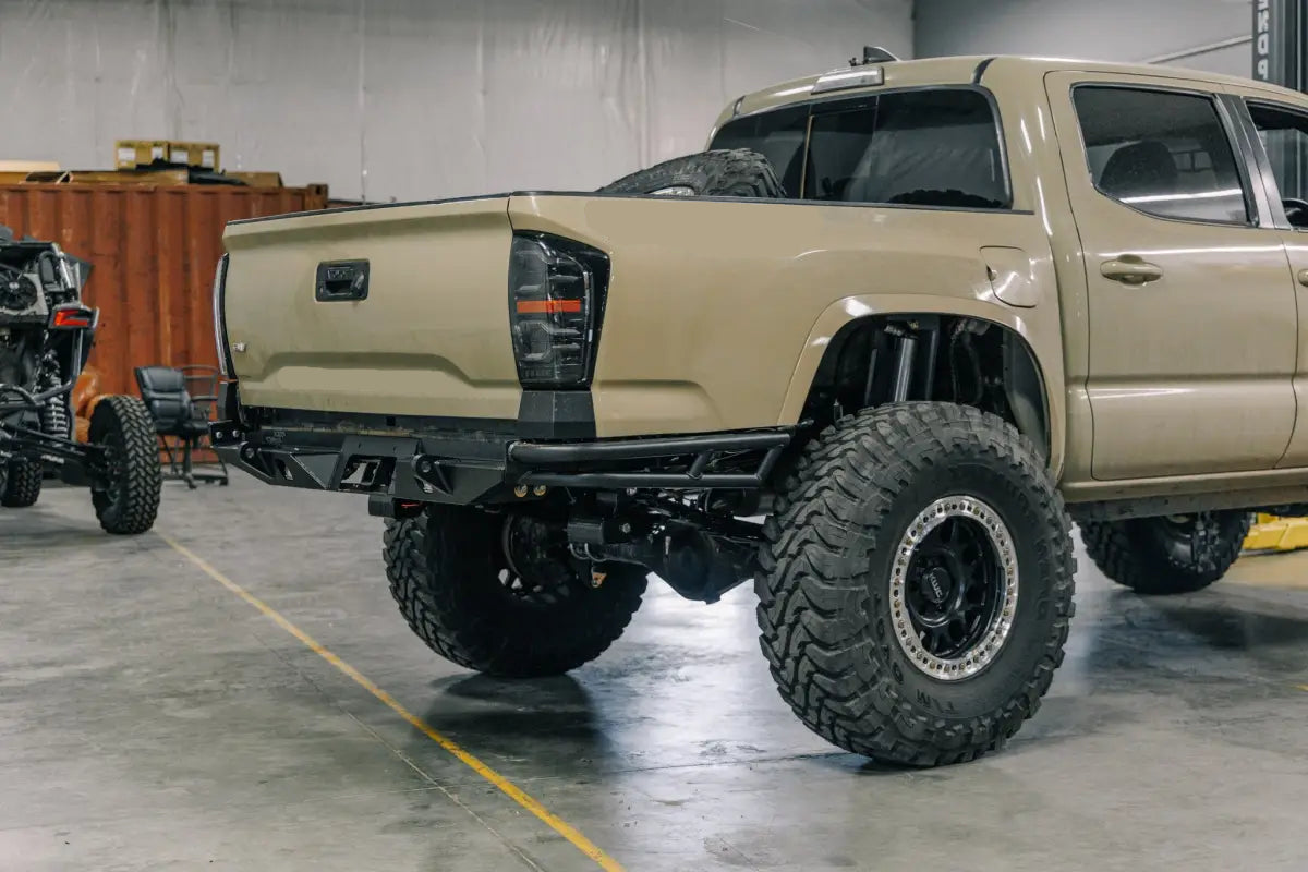 Beige 3rd Gen Tacoma equipped with a double tube Tacoma Rock Runner rear bumper, emphasizing off-road readiness in a garage.
