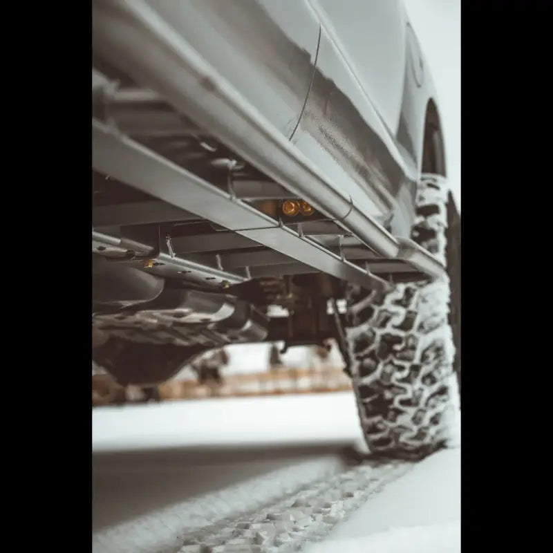 Underside view of Tundra 2nd Gen rock sliders in snowy conditions, emphasizing strong mounting and frame protection.