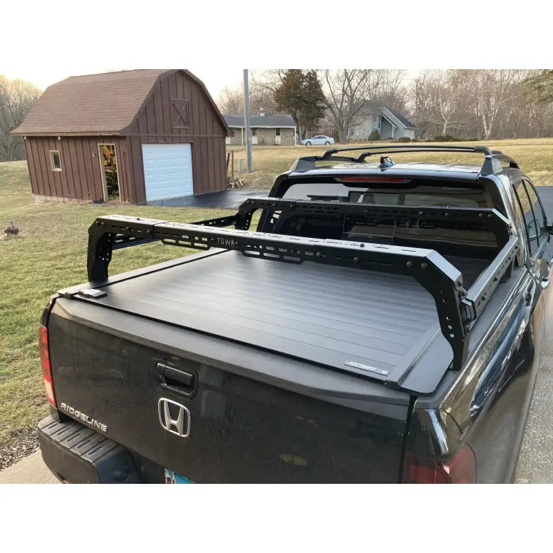Black Honda Ridgeline with TUWA PRO®️ mid-height bed rack installed over a retractable tonneau cover, enhancing cargo versatility.