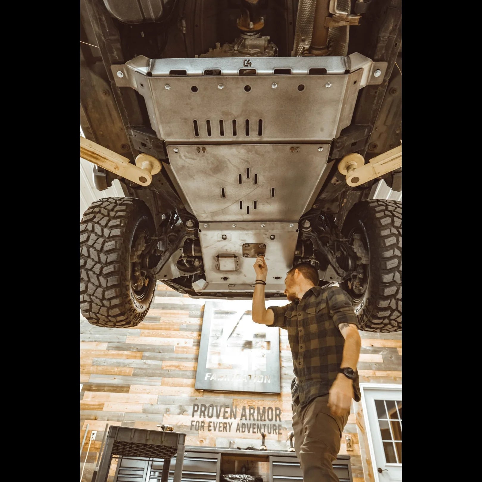 Mechanic inspecting 5th Gen 4Runner skid plates designed for engine and transmission protection, showcasing durable off-road armor.