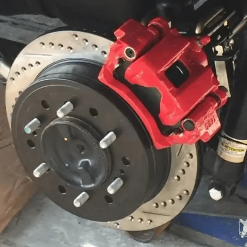 Toyota Tacoma rear disc conversion kit installed with red caliper, drilled rotor, and 6-lug setup for enhanced braking performance.