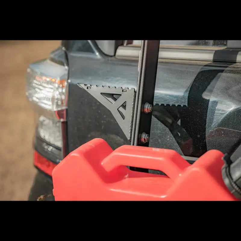 Black 4Runner Summit Hatch Ladder Side Step mounted on a ladder, paired with a red fuel container for off-road gear storage.