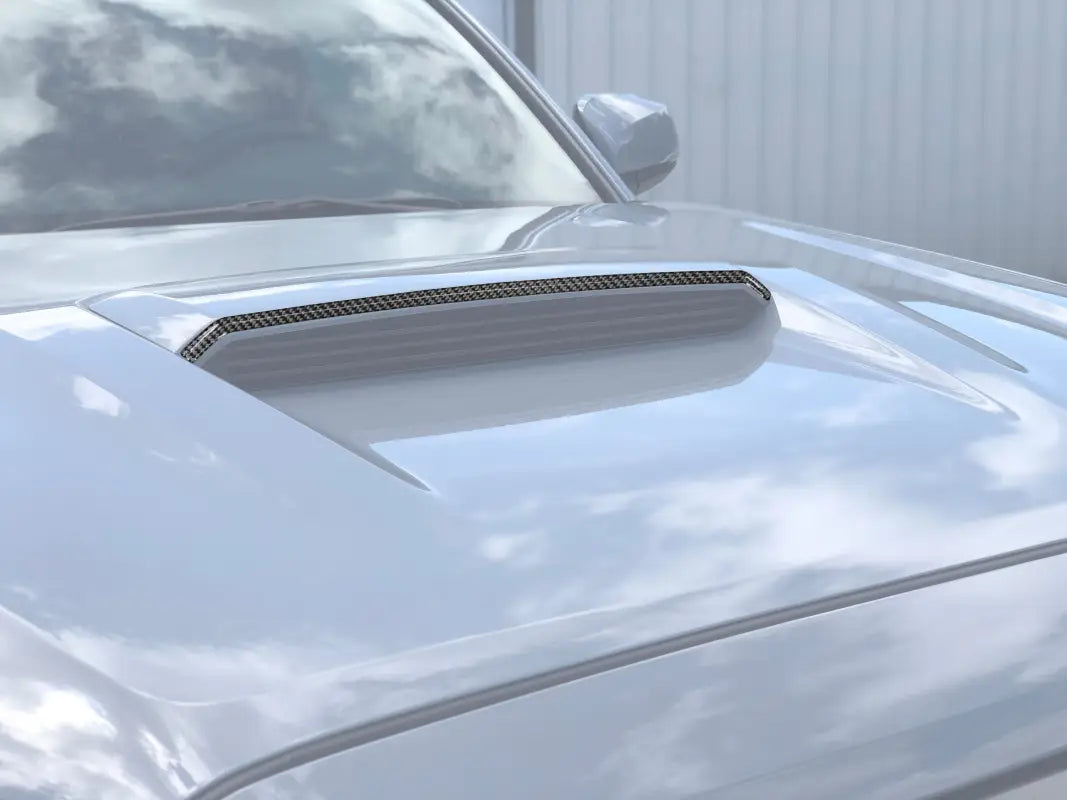 Upper hood scoop accent trim in carbon fiber finish installed on a 2016-2023 Toyota Tacoma TRD Pro/Sport, enhancing the vehicle's exterior style.
