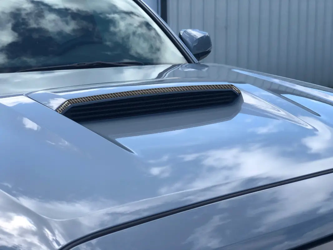 Close-up of carbon fiber upper hood scoop accent trim on a 2016-2023 Toyota Tacoma TRD Pro/Sport, showcasing its sleek design.